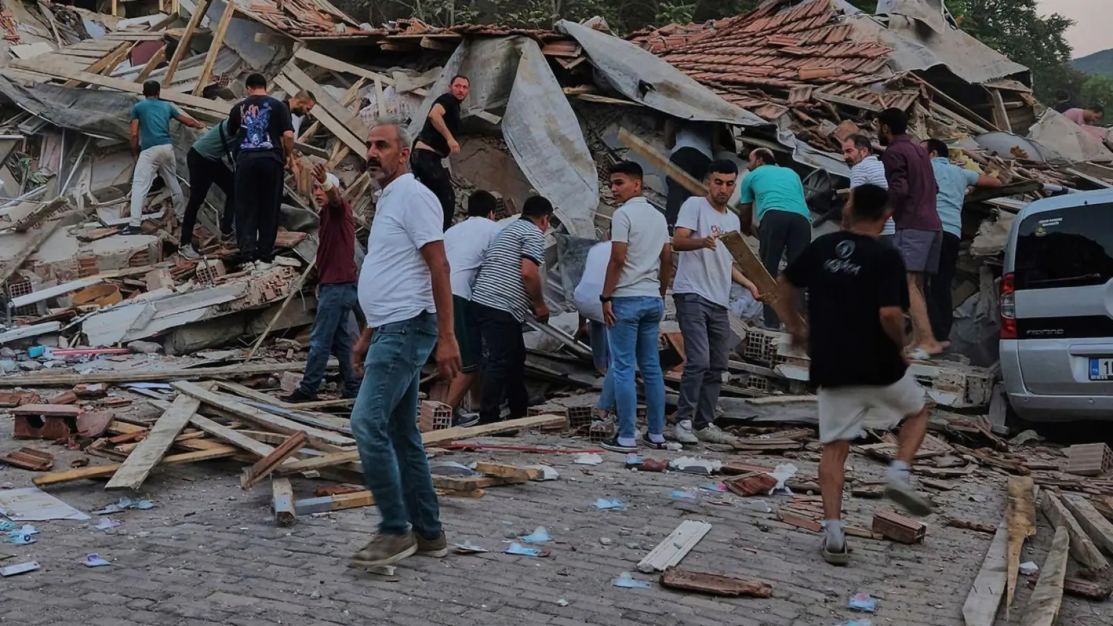 Menschen beseitigen in Sindirgi die Trümmer eines eingestürzten Gebäudes. (Foto: Bahadir Demirceviren/IHA/AP/dpa)