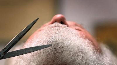Einem Mitwirkenden der Passionsspiele wird in einem Friseur-Salon der Bart gestutzt. (Foto: Karl-Josef Hildenbrand/dpa)