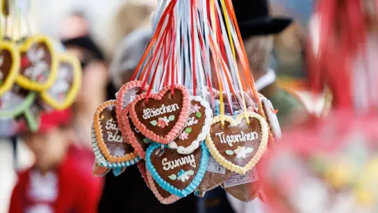 Lebkuchenherzen mit Kosenamen hängen an einem Stand auf einem Volksfest. (Foto: Matthias Balk/dpa)