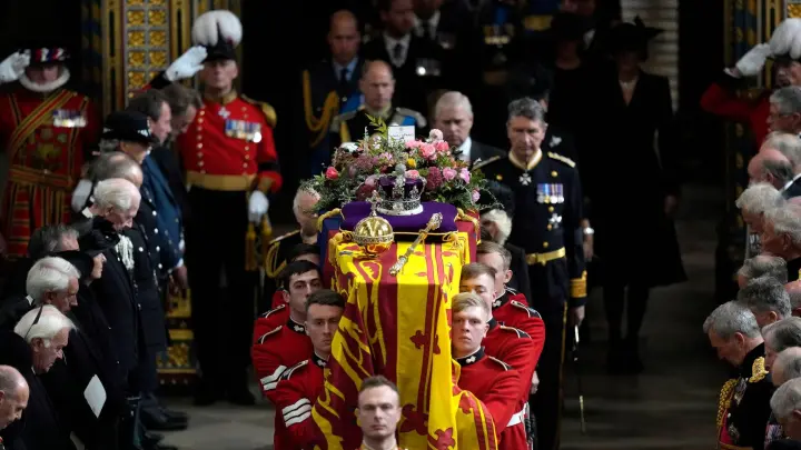 Mitglieder der königlichen Familie folgen dem Sarg von Königin Elizabeth II., der von mehreren Männern getragen wird. (Foto: Frank Augstein/Pool AP/dpa)