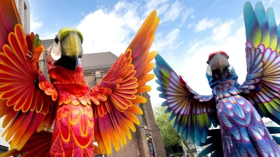 Zwei Papagei-Statuen stehen für die Eröffnungsparade des Figurentheaterfestivals Fidena in Bochum auf der Straße. Mit übergroßen Insekten und seltsamen Lebewesen wurde ein Statement gegen das Artensterben gesetzt. (Foto: Dieter Menne/dpa)