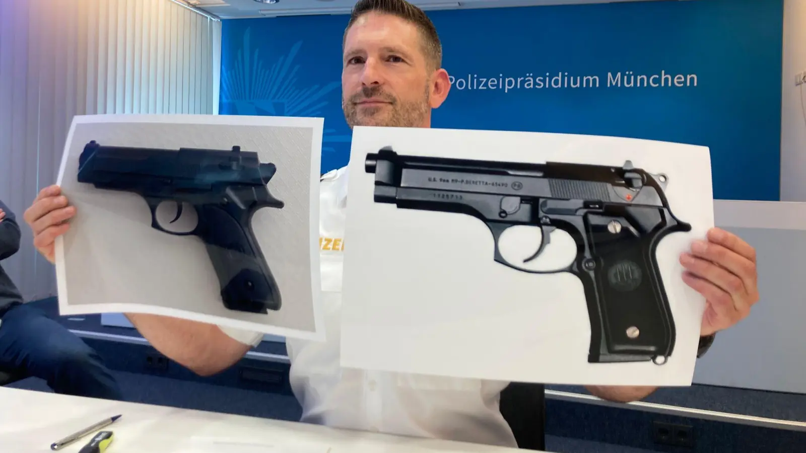 Polizeisprecher Thomas Schelshorn zeigt Fotos der Softair-Waffe und der echten Waffe.  (Foto: Sabine Dobel/dpa)