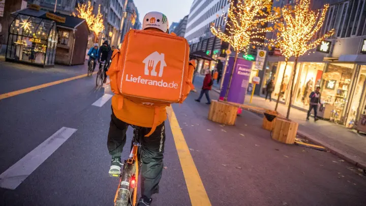 Ein Kurierfahrer des Restaurantlieferdiensts  Lieferando fährt mit seinem Fahrrad über die Friedrichstraße in Mitte in Berlin. (Foto: Michael Kappeler/dpa)