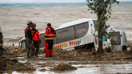 Rettungskräfte auf Ischia neben einem Bus, der durch schwere Regenfälle weggeschwemmt wurde. (Foto: Salvatore Laporta/AP/dpa)