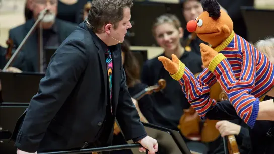 Dirigent David Claessen im Gespräch mit Ernie während des Familienkonzerts im Großen Saal der Elbphilharmonie. (Foto: Georg Wendt/dpa)