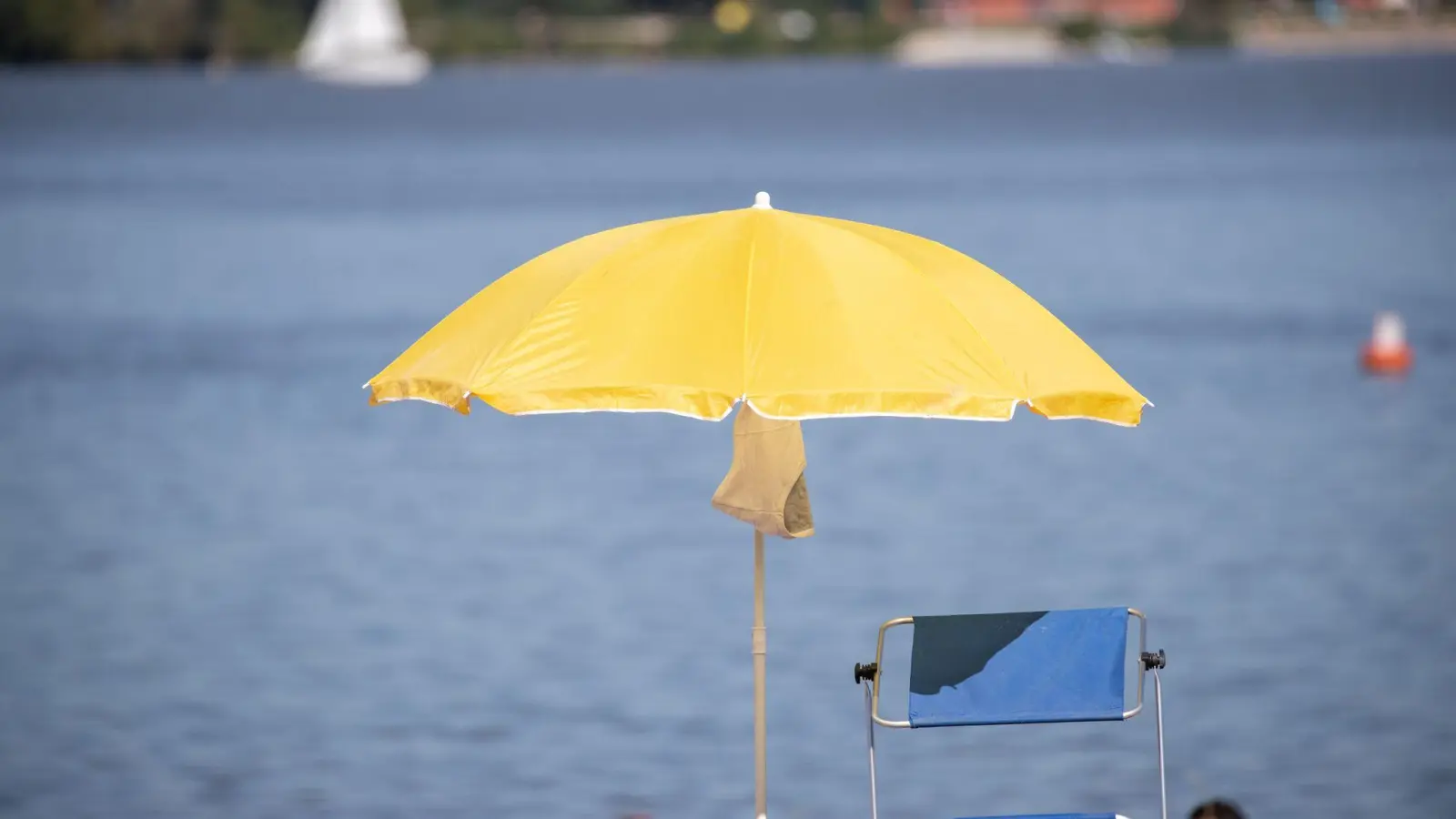 Ein Sonnenschirm steht an einem Strand am Altmühlsee. (Foto: Daniel Karmann/dpa/Archivbild)
