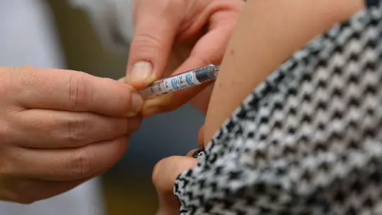 Ein Arzt impft eine Frau gegen die Grippe. (Foto: Robert Michael/dpa-Zentralbild/dpa/Symbolbild)