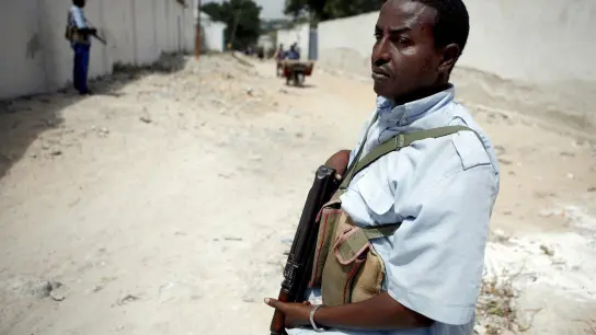 Ein schwer bewaffnetet Soldat hält in Mogadischu Wache: Die Terrorgruppe Al-Schaabab verübt immer wieder Anschläge auf Sicherheitskräfte und Zivilisten. (Foto: picture-alliance/dpa)
