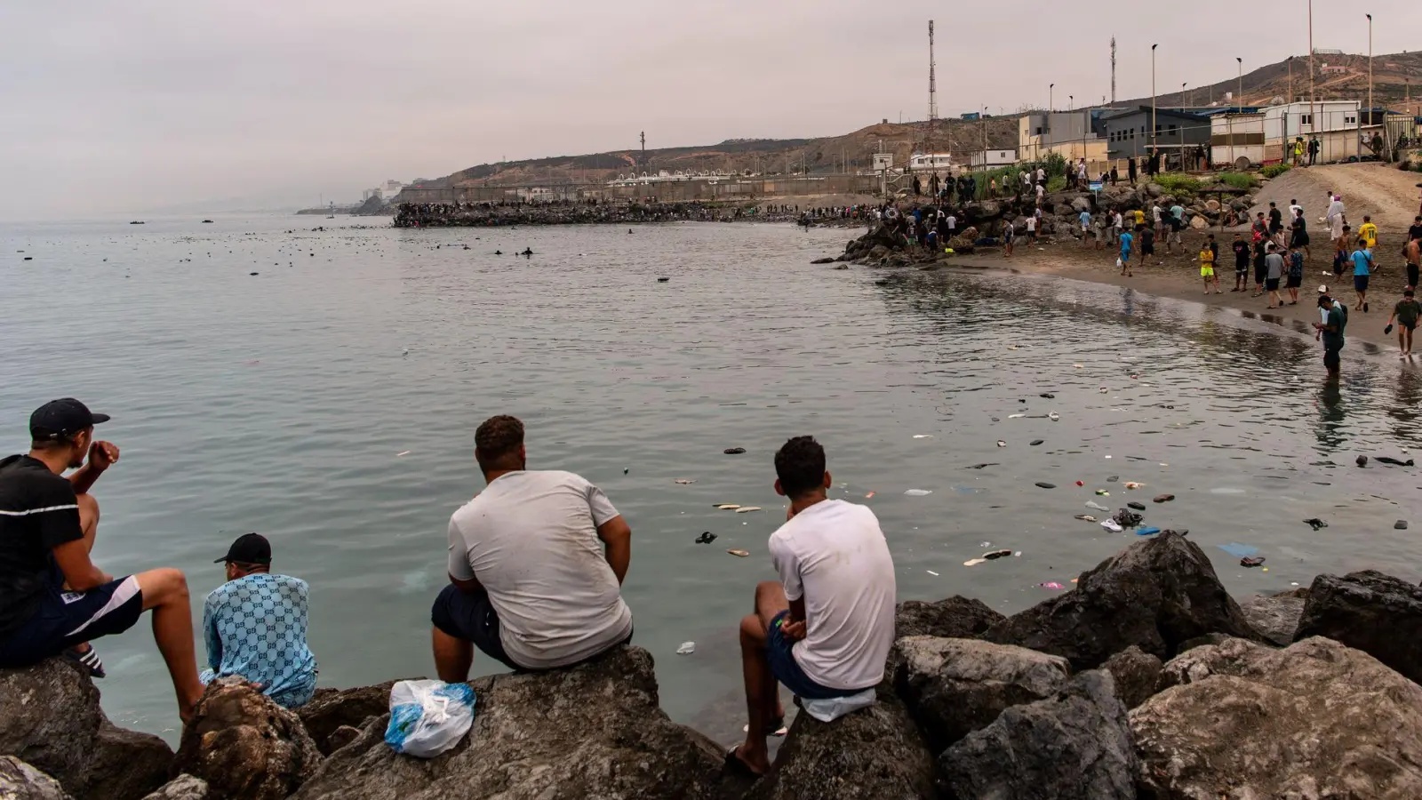 Migranten blickten von Felsen aus, während andere aus der spanischen Enklave Ceuta nach Marokko zurückkehrten. (Foto: Antonio Sempere/AP/dpa)