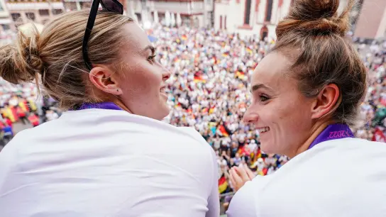 Die Spielerinnen Laura Freigang (l) und Lina Magull lassen sich auf dem Balkon des Römer von den Fans feiern. (Foto: Uwe Anspach/dpa)