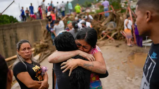 Anwohner umarmen sich nach dem durch heftigen Regen verursachten Erdrutsch in Las Tejerias. (Foto: Matias Delacroix/AP/dpa)