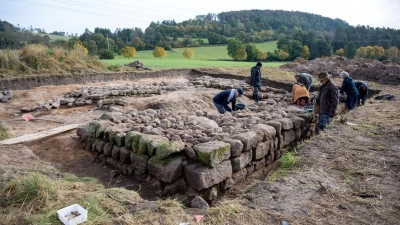 Freiwillige Helfer der Archäologischen Arbeitsgruppe Kronach legen die Steinfundamente eines Turms aus dem 12. Jahrhundert frei. (Foto: Pia Bayer/dpa/Archivbild)