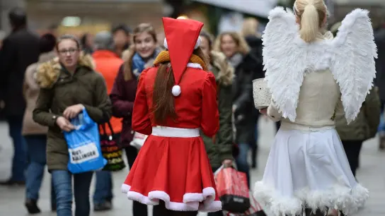 Zwei als Weihnachtsmann und Engel verkleidete Frauen verteilen in Münchens Innenstadt Lebkuchen. (Foto: Andreas Gebert/dpa/Symbolbild)