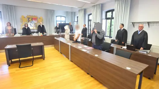 Eine Jugendlicheund ein Erwachsener stehen in einem Gerichtssaal des Landgerichtes vor der Anklagebank.Die beiden sind angeklagt, gemeinsam eine 16-Jährige getötet zu haben. (Foto: Karl-Josef Hildenbrand/dpa)