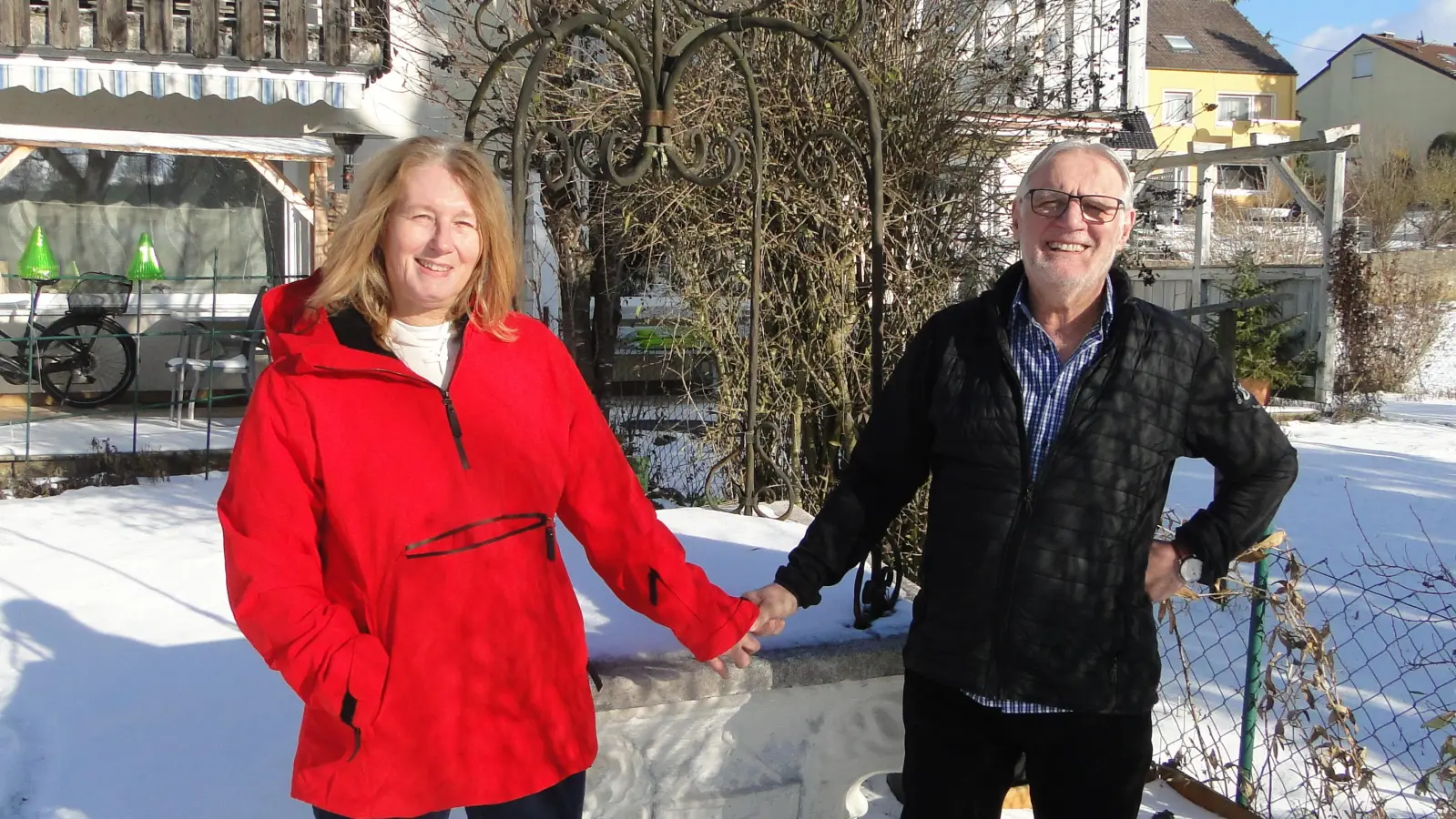 Andrea und Theo Mutsios in ihrem verschneiten Garten in Hennenbach vor dem Brunnen, der früher in ihrem Lokal stand und Andrea jetzt im Sommer als Hochbeet dient. (Foto: Winfried Vennemann)