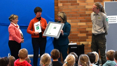 Claudia Wust, Bürgermeisterin und Vorsitzende des Schulverbands, und Schulleiterin Kerstin Stiegler bekommen von Renate Hans, der Vorsitzenden des Naturparks Frankenhöhe (von links), die Urkunde als Naturpark-Schule und ein Schild für den Eingang. Aufmerksame Beobachter sind Ranger Benjamin Krauthahn und die Kinder der Grundschule. (Foto: Manfred Blendinger)