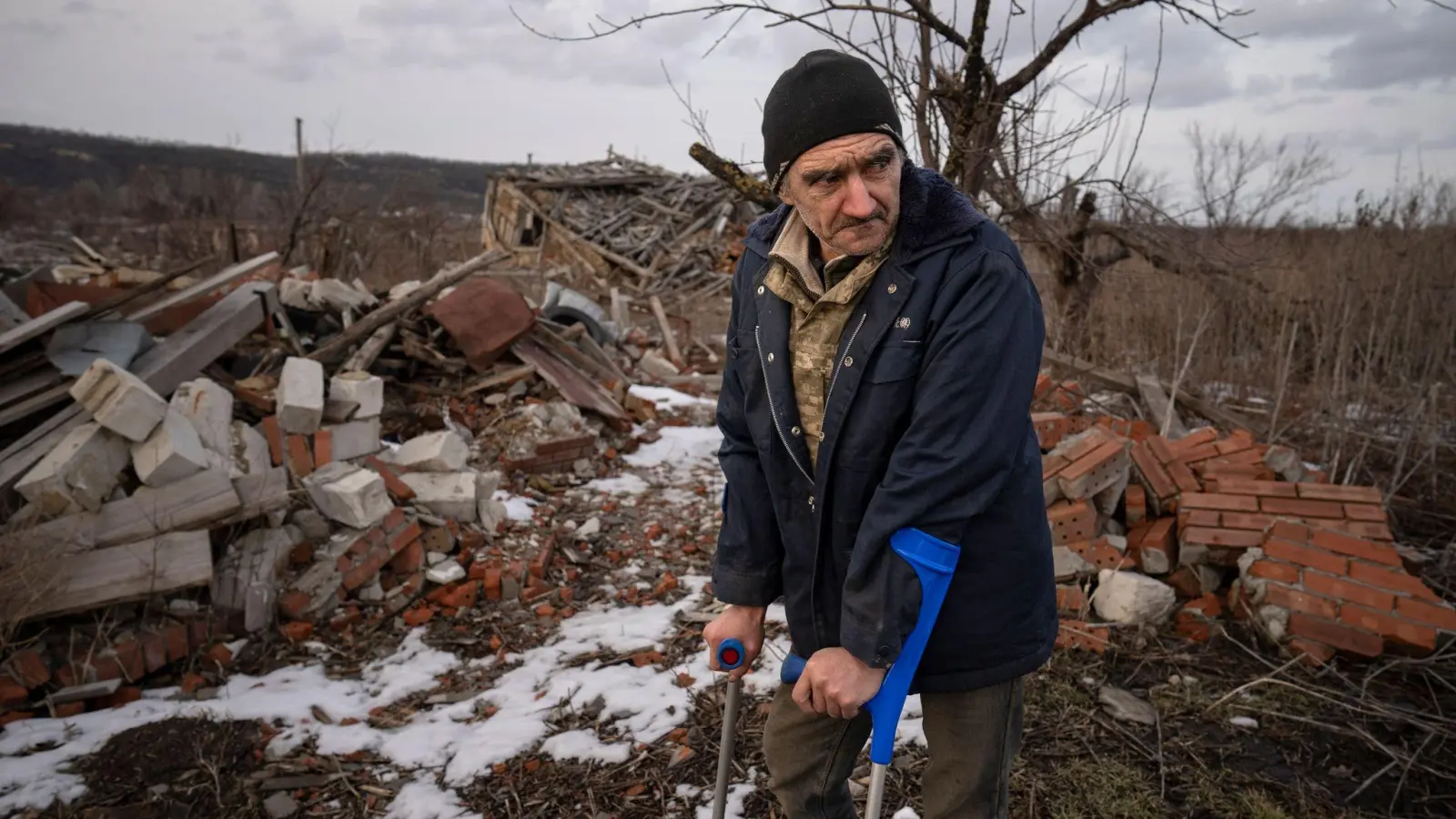 Andrii Cherednichenko (50), der von einer Landmine verletzt wurde, steht auf Krücken vor den Ruinen seines Hauses im ukrainischen Kamjanka. (Foto: Vadim Ghirda/AP/dpa)