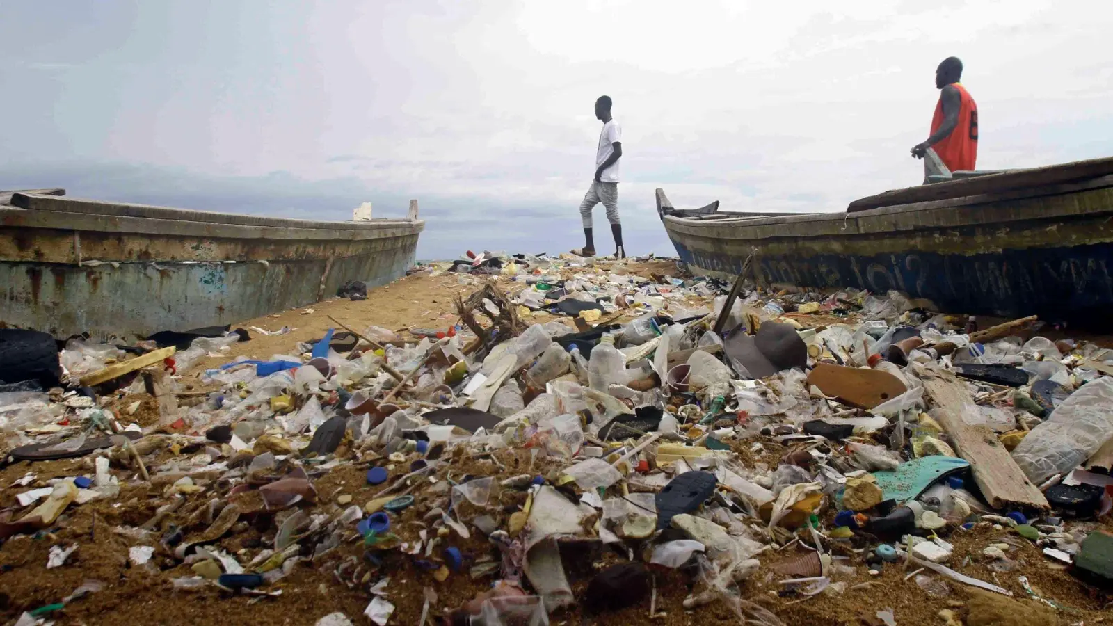 Menschen spazieren über einen mit Plastik verschmutzten Strand an der Elfenbeinküste. (Foto: Diomande Ble Blonde/AP/dpa)