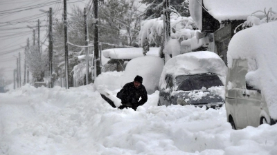 Ein Mann in Isperich schaufelt Schnee, um sein Auto zu befreien. (Foto: Mehmed Aziz/AP/dpa)
