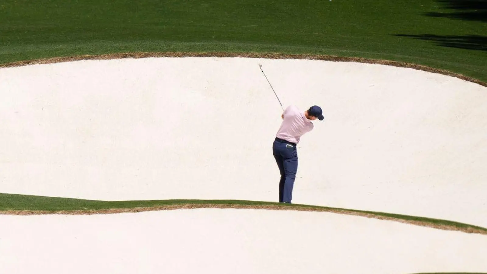 Spannung in der Ferne: Der Golfspieler Rory McIlroy aus Nordirland schlägt am achten Loch. Seit 1934 findet das Golfturnier US Masters auf demselben Golfplatz in Georgia, USA statt. (Foto: Charlie Riedel/AP/dpa)