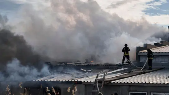 Feuerwehrleute des staatlichen ukrainischen Katastrophenschutzes löschen ein Feuer, das nach Beschuss eines Industriegebiets in Cherson ausgebrochen ist. (Foto: Libkos/AP/dpa)