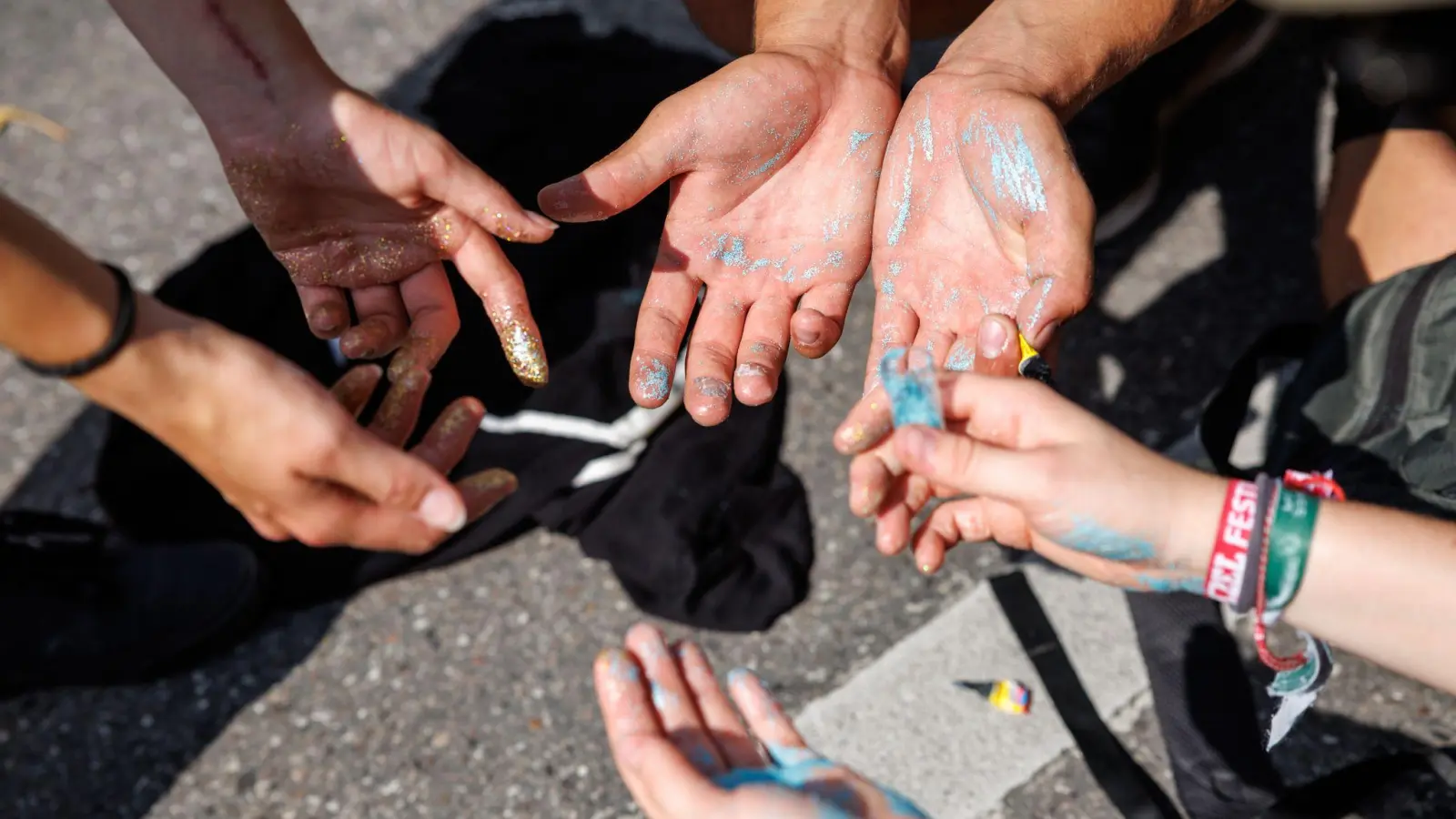 Aktivisten färben ihre Finger während einer Protestaktion vom Bündnis „No Future for IAA“ im Rahmen der IAA MOBILITY 2023 mit buntem Glitzer ein. (Foto: Matthias Balk/dpa)