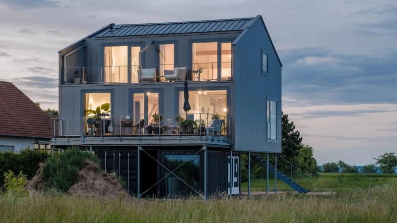 Das Stelzenhaus am Abend: „Teilunterkellert” wurde es mit zwei alten Schiffscontainern. In einem davon befindet sich die Haustechnik. (Foto: Markus Vogt)