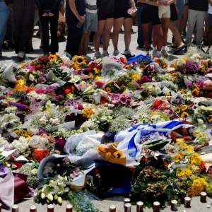 Menschen versammelt sich einen Tag nach einer Schießerei am Bondi Beach in Sydney um ein Blumendenkmal. (Foto: Mark Baker/AP/dpa)