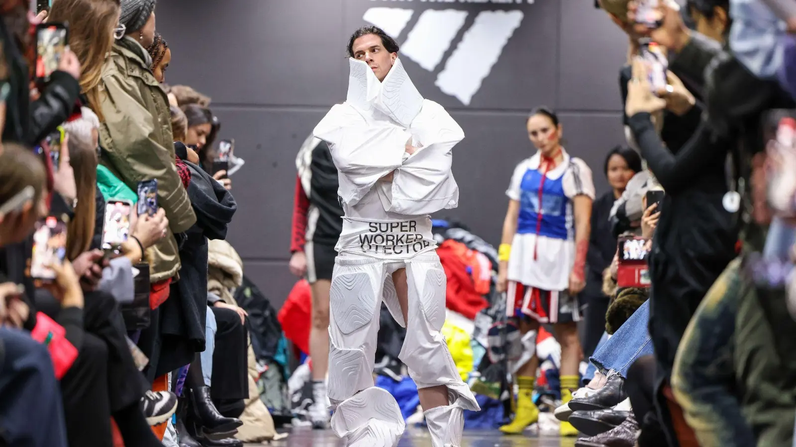 Ein Aktivist bei einer als Adidas-Show getarnten Performance auf dem Catwalk. (Foto: Gerald Matzka/dpa)