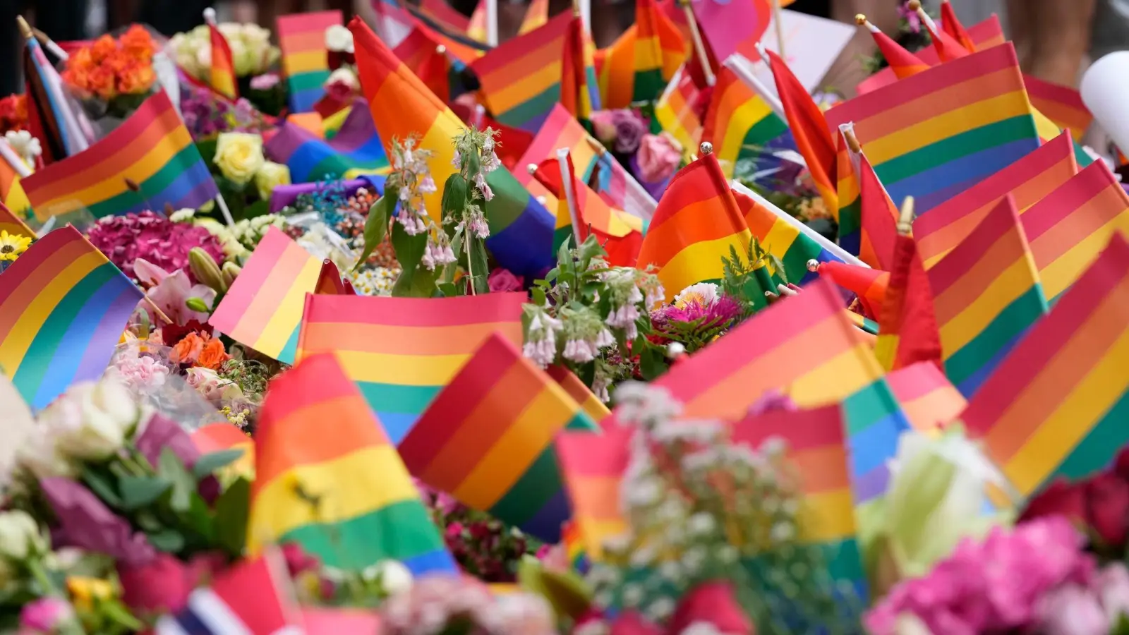 Blumen und Regenbogenfahnen liegen nach den tödlichen Schüssen in einer Schwulen-Bar in Oslo vor dem Tatort. (Foto: Sergei Grits/AP/dpa)