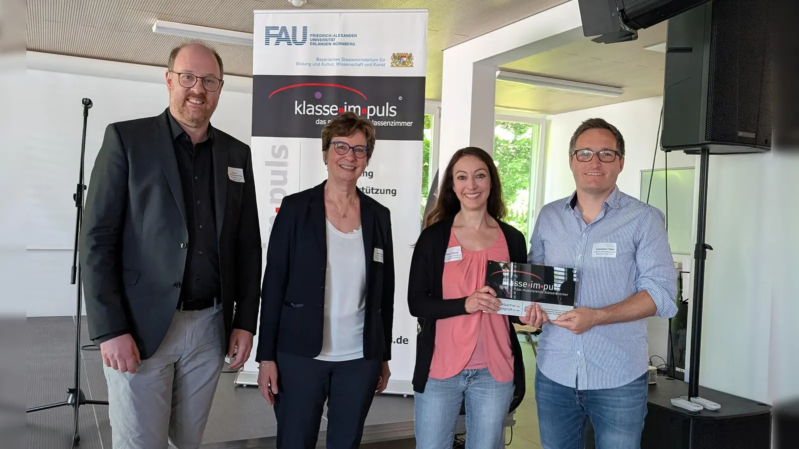 Professor Dr. Johannes Hasselhorn von der Friedrich-Alexander-Universität Erlangen-Nürnberg, Ministerialdirigentin Eva Schwab sowie die Lehrkräfte Helen Gibson und Sebastian Felbel (von links) freuen sich über die Auszeichnung. (Foto: Christoph Utz)