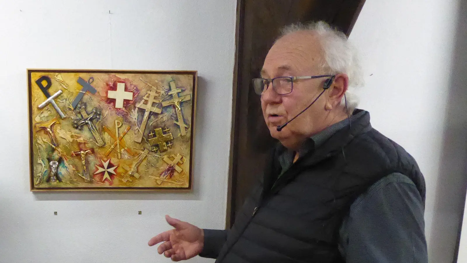 Der Herrieder Künstler Martin Kiss erläutert anhand einer von ihm eigens geschaffenen Collage die verschiedenen Kreuzesformen. (Foto: Rudolf Eder)