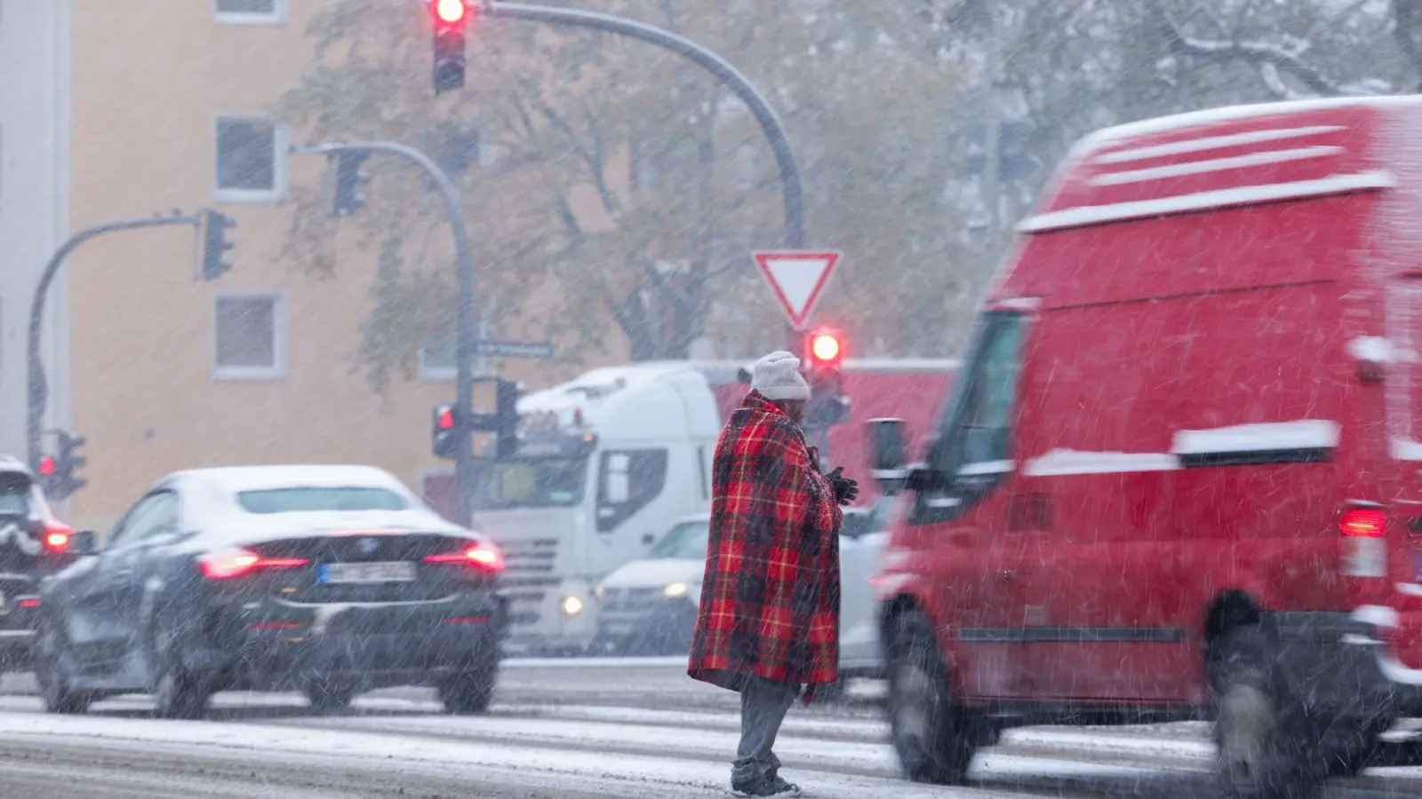 Zwischen wartenden Autos an der Ampel: Bitte um Almosen bei Schneetreiben in Hamburg. (Foto: Christian Charisius/dpa)