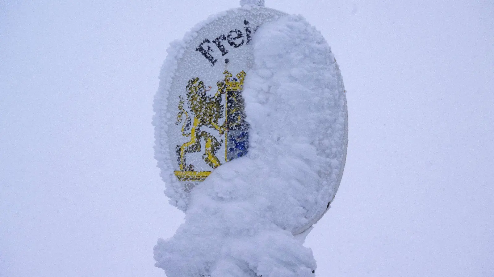 Ein verschneites Schild mit dem Wappen des Freistaats Bayern steht auf dem Gipfel der Zugspitze. (Foto: Peter Kneffel/dpa)