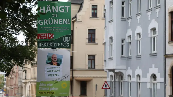 Ein umstrittenes Wahlplakat der Splitterpartei „III Weg” hängt über einem Plakat der Grünen. (Foto: Bodo Schackow/dpa-Zentralbild/dpa/Archivbild)
