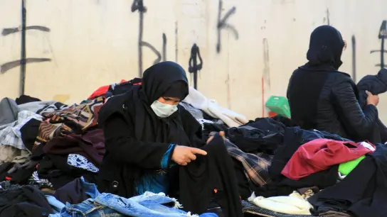 Eine Kundin schaut sich gebrauchte Kleidungsstücke auf einem zentralen Markt in Tunesiens Hauptstadt an. (Foto: Cindy Riechau/dpa)