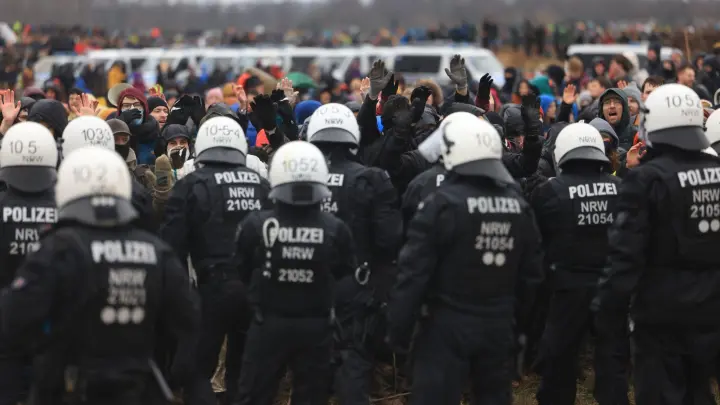 Polizisten und Demonstranten stehen sich bei der Demonstration von Klimaaktivisten am Rande des Braunkohletagebaus bei Lützerath gegenüber. (Foto: Oliver Berg/dpa)