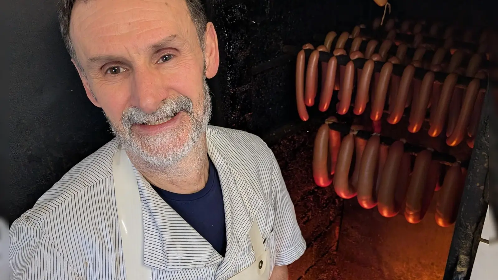 Metzgermeister Friedrich Menhorn kontrolliert das Buchenholzfeuer, über dem die Würste geräuchert werden. (Foto: Friedrich Zinnecker)