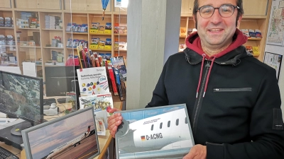 Aktuell trägt eine Cityline-Maschine des Herstellers Bombardier den Namen Rothenburg durch die Lüfte. Robert Nehr vom Tourismus-Service präsentiert zwei dort aufbewahrte Fotos, die das Flugzeug im Ganzen und eine Detailaufnahme des Schriftzugs mit dem Namen zeigen. (Foto: Jürgen Binder)