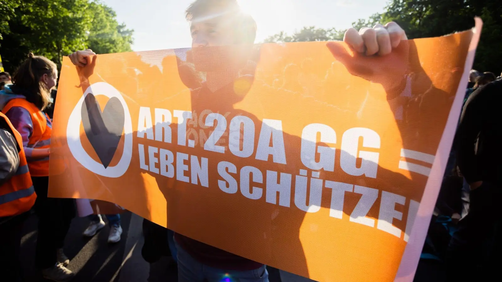 Ein Teilnehmer einer Demonstration der Letzten Generation hält ein Banner. (Foto: Christoph Soeder/dpa)