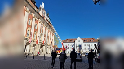 Der ungewöhnliche Einsatz der Feuerwehr an der Rathaus-Uhr in Bad Windsheim erregte bei den vorbeigehenden Menschen große Aufmerksamkeit. (Foto: Josh Reuter)