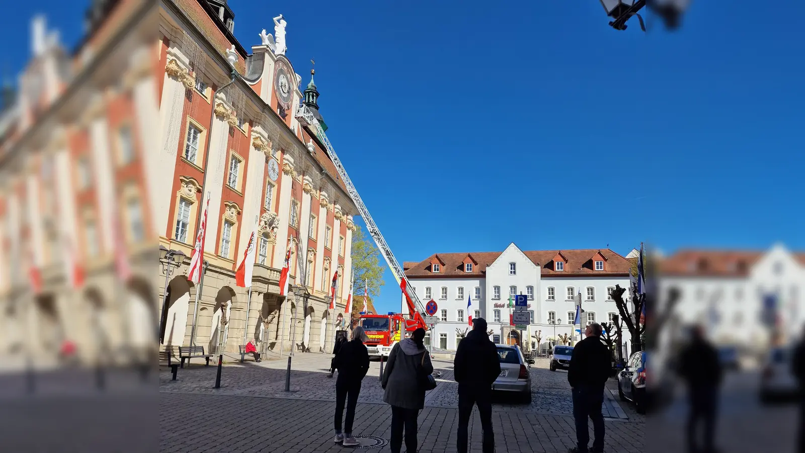 Der ungewöhnliche Einsatz der Feuerwehr an der Rathaus-Uhr in Bad Windsheim erregte bei den vorbeigehenden Menschen große Aufmerksamkeit. (Foto: Josh Reuter)