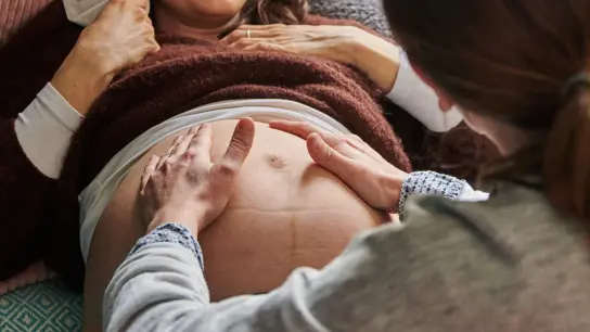 Eine Hebamme tastet in ihrer Berliner Praxis den Bauch einer schwangeren Frau ab. (Foto: Annette Riedl/dpa)