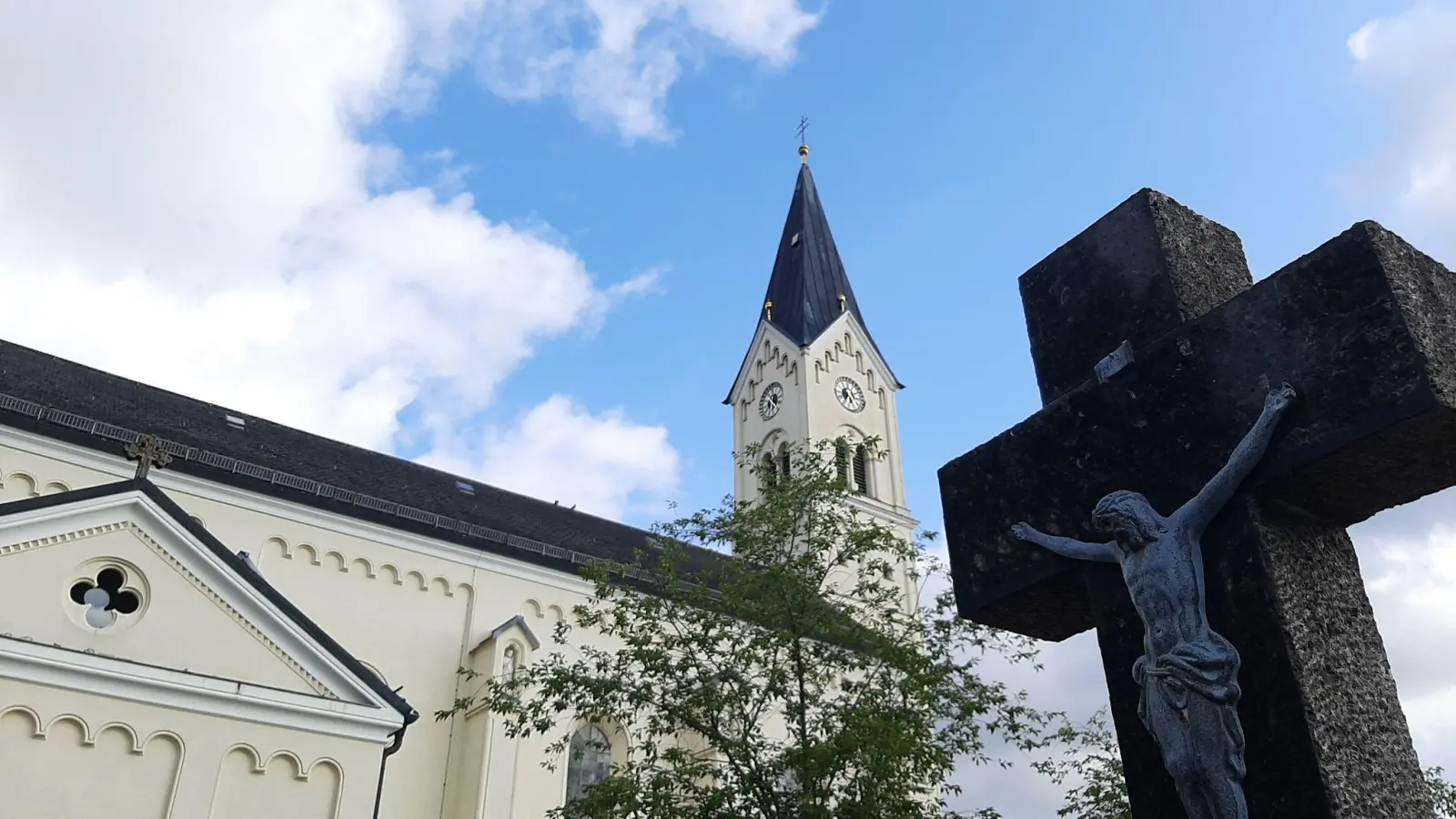 Ein Kreuz steht vor der Kirche St. Nikolaus in Garching an der Alz. (Foto: Britta Schultejans/dpa/Archivbild)