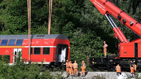 Ein Waggon von dem verunfallten Regionalzug  hängt für die Bergung an dem Schienenkran. (Foto: Angelika Warmuth/dpa/Symbolbild)
