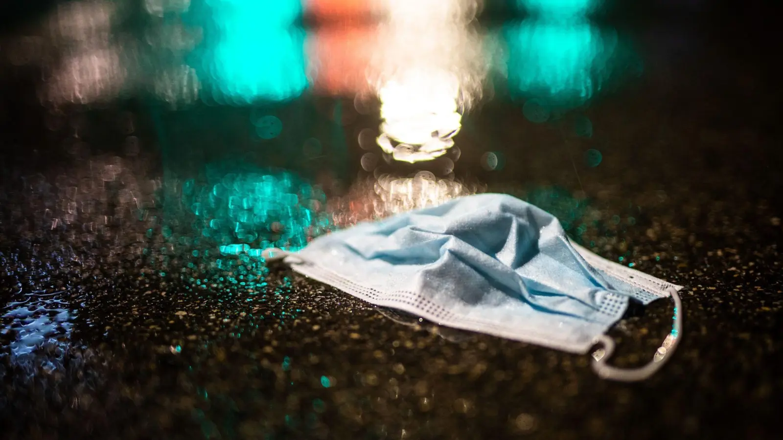 Ein Mund-Nasenschutz liegt im Regen auf der Strasse. (Foto: Christoph Schmidt/dpa/Symbolbild)