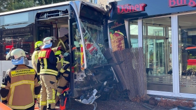 Einsatzkräfte der Feuerwehr untersuchen den  Linienbus, der zuvor in einen Dönerladen gekracht war. (Foto: Schröder/NEWS5/dpa)
