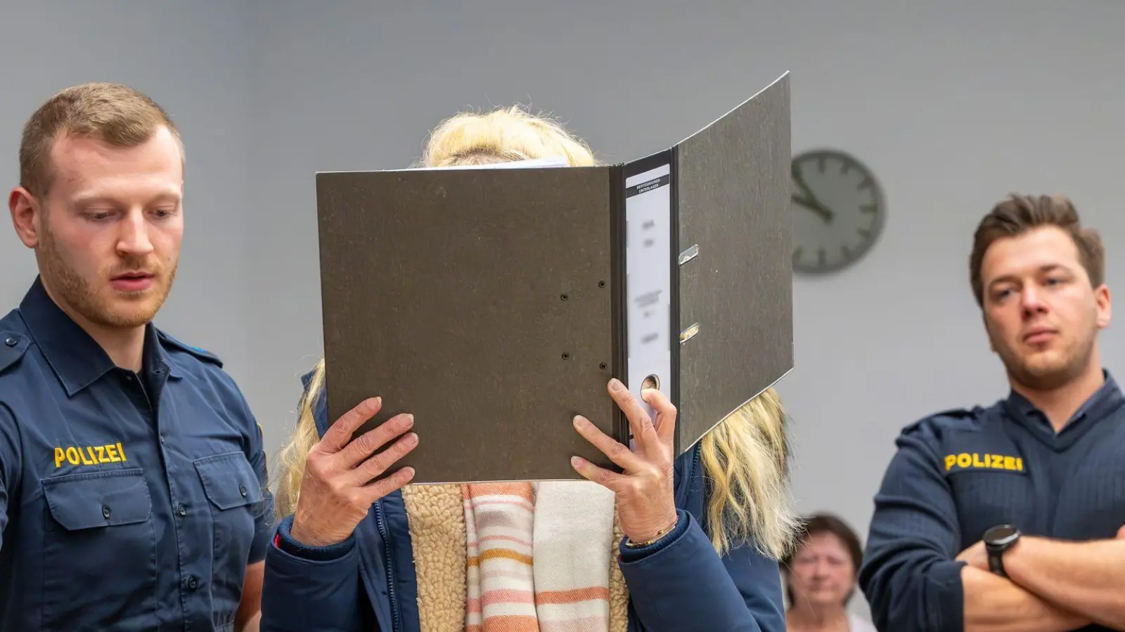 Die Angeklagte versteckte ihr Gesicht hinter einem Aktenordner.  (Foto: Peter Kneffel/dpa)
