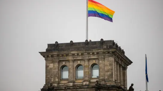 Die Regenbogenfahne wird anlässlich des Berliner Christopher Street Day (CSD) auf dem Südwestturm des Reichstagsgebäudes gehisst. (Foto: Christoph Soeder/dpa)