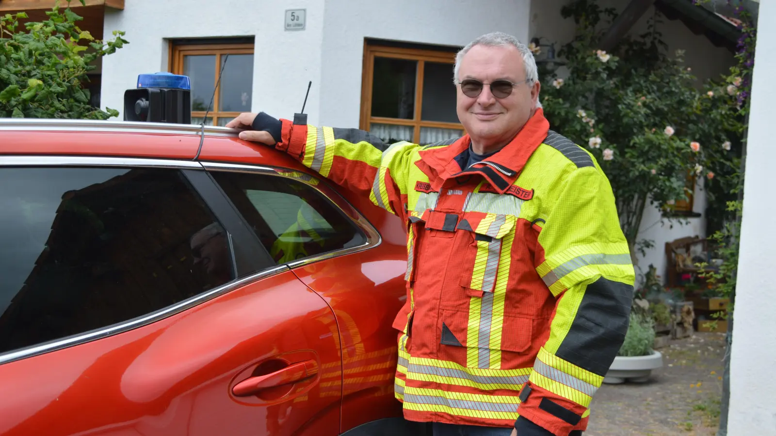 Rüdiger Neumeister mit seinem „Einsatzfahrzeug“. Aufsetzblaulicht, Feuerwehruniform, Helm und alles, was man eben so braucht, hat er im Kofferraum seines mobilen Feuerwehrhauses immer dabei. (Foto: Johannes Zimmermann)